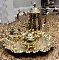 Full tea set arranged on wooden floor showing teapot, sugar bowl with lid, creamer, and tray
