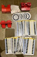 Photo of three vintage 3D viewers and multiple slide sets arranged on a surface. Red View-Master, Stereoscope Simplex, and Storie-Views viewers visible along with round and rectangular slides.