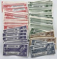 A collection of Canadian Tire Money bills sorted by denomination showing five cents (green), ten cents (red), twenty-five cents (blue), fifty cents (brown), and one dollar (black/grey).