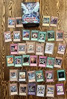 Galaxy-Eyes White Dragon metal tin surrounded by laid-out Yu-Gi-Oh! cards on wood surface