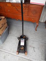 Top view of the jack handle, showing black metal body and wooden floor background