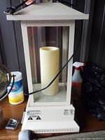 Front view of Duraflame portable heater with glass panels, power cord, and artificial candle inside.