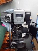 Wide view of electronic equipment including stereo system, speakers, keyboard, and cables arranged on the floor