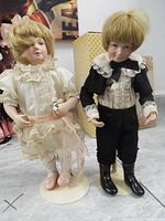 Both Franklin Heirloom dolls Alicia and Andrew standing side by side on metal stands, showing full outfits and faces