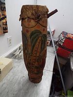 Full view of the 27-inch drum standing upright showing the carved and painted palm tree design, drumhead, and overall condition with worn and scratched surface.