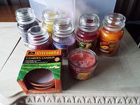 Photo of six large glass jar candles by Yankee Candle, one small glass jar candle, and a boxed set of citronella garden candles on a table