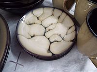 Close-up of smaller plate showing beige crackled glaze with dark lines.