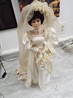 Full view of porcelain doll in white bridal dress with veil and bouquet.