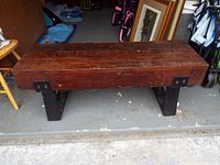 Front view of wooden bench showing distressed wooden top and metal leg stands