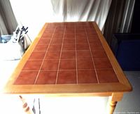 Full view of rectangular table showing tiled top and wooden legs