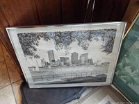 Framed black and white cityscape print resting against wood panel wall