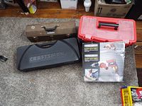 Overview of tool lot showing three tool cases and a boxed drill on carpeted floor.