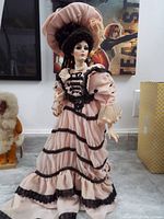 Full-body image of the doll showing the Victorian-style pink dress with black lace accents and bonnet.