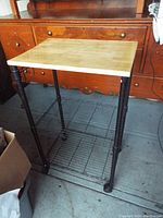 Front angle of rolling cart showing solid wood top, metal legs, and wire shelf underneath on caster wheels