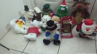 Front view of grouped Christmas animated decorations on floor including snowmen, reindeer, bear, and Santa's Outhouse.