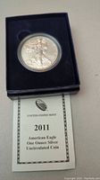 Front view of silver coin in presentation case along with certificate showing year 2011 and details.