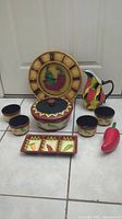 Full set displayed including wall clock, pitcher, covered dish, four cups, divided tray, and chili pepper shaped item