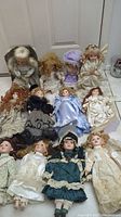 Photo showing all 12 collectible porcelain dolls together, arranged sitting on the floor, showcasing their varied clothing and hairstyles.