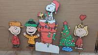 Overview of five wooden Peanuts character and tree cutouts against exterior wall
