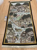 Full view of the extra-large hand-painted fabric mural laid flat with a water bottle placed for scale. Depicts Asian village with river, buildings, trees, and people in traditional attire.