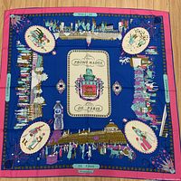 Full view of the large square silk scarf displaying vibrant Paris-themed design with bottle for scale.