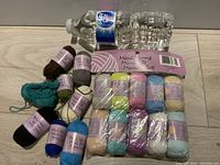 Photo showing miniature yarn skeins wrapped in pastel purple labels, small teal and black knitted swatches.