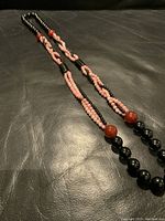 Full view of the long beaded necklace featuring black onyx and carnelian beads laid flat on a black surface.