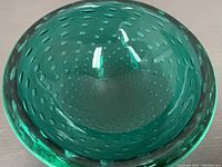 Top view of a green Murano glass bowl showing the controlled bubble pattern inside and the glossy finish.