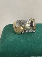 Front right-angle view showing bezel-set pear-shaped garnet and textured white accent panels.