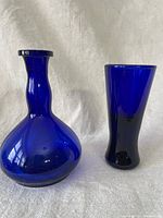Photo showing the larger vase with bulbous base and narrow neck on left; smaller straight flared vase on right.