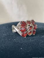 Photo of ring on black background showing floral arrangement of multi red stones set in sterling silver band