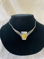 Front view of a sterling silver Art Deco style choker necklace with a yellow marbled stone centerpiece, displayed on a black bust.