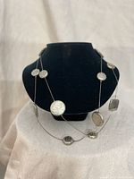 Sterling silver necklace draped twice on a black necklace display showing pendants spaced along chain