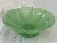Front angled view of the vintage green jadeite ribbed candy bowl showing the scalloped rim and pedestal base.