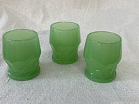 Three small jadeite juice cups with textured pattern, shown upright on a flat surface.