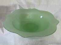 Top view showing the scalloped edge and round shape of the light green jadeite bowl.