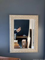 Full view of the mirror hanging on the wall showing its rectangular shape and carved frame.
