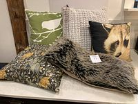 Five pillows grouped on a surface showing all designs and textures in one image