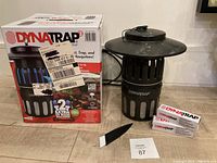 Photo showing the DynaTrap mosquito trap with original box, two extra UV light bulbs, small cleaning brush, and a lot number card.