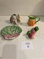 Five ceramic Fitz & Floyd figural pieces including bunny with lid, carrot creamer, radish salt and pepper shakers, and radish plate arranged on a countertop