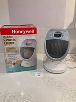 Photo showing Honeywell oscillating ceramic heater next to its original box on countertop.