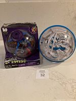 Perplexus Twist ball in original purple box with branding and toy visible next to it on the counter.