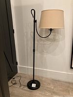 Full view of standing lamp showing the curved arm and cream lampshade