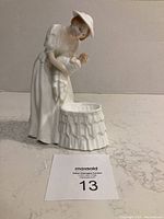 Front angled view of Royal Doulton figurine showing woman holding baby above cradle