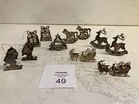 All eleven silver-coloured lightweight Christmas ornaments displayed on marble surface. Items include 2 Santa on skis, 2 bells, 2 rocking horses, 2 reindeer, 2 Santa with sleigh, and 1 Christmas tree ornament.