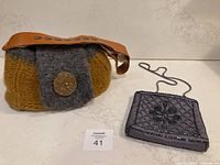 Photo of two purses: a yellow and grey hand knitted purse with large pottery button and brown repurposed belt shoulder strap, and a grey beaded evening bag with a cord shoulder strap.