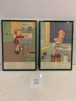 Two framed vintage child prints, one showing a boy at a table with a dog, the other with a child standing on a stool at a sink.