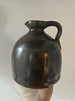 Front view of the dark brown glossy glazed earthenware batter jug showing bulbous body and handle.