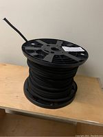 Full view of black plastic reel with black bungee shock cord wound around it, showing length and thickness.
