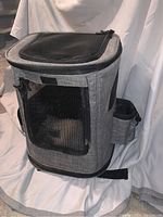 Photo of gray cat carrier backpack showing mesh windows on front and side, with black trim and fabric body.